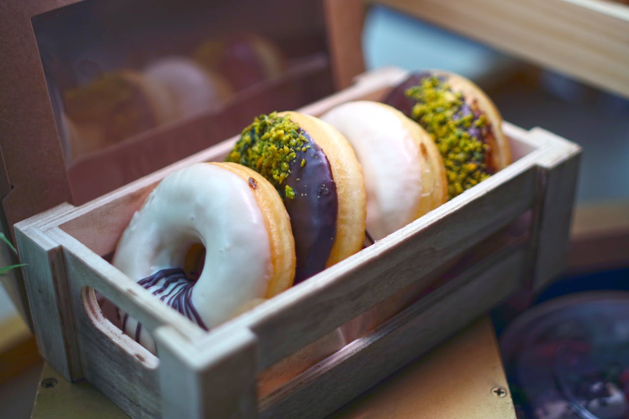 about-01 A close-up of delicious assorted donuts with various toppings presented in a rustic wooden box.