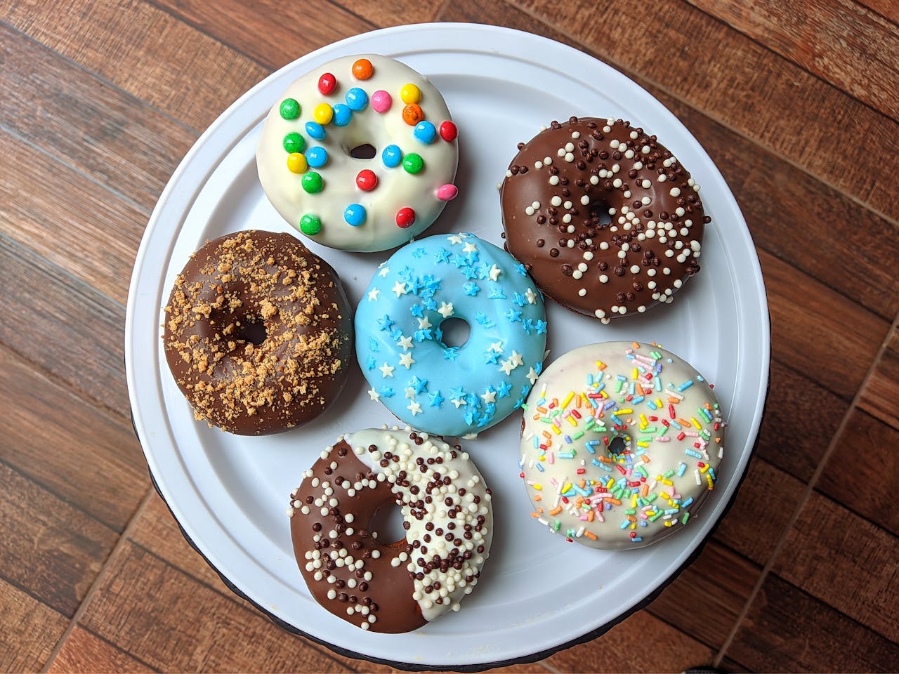 services-02 A vibrant assortment of decorated donuts placed on a white plate, perfect for any dessert lover.